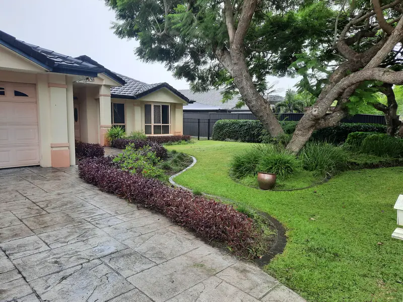 The same front garden after the tidy-up, with a crisp curved lawn edge, trimmed beds and a clean driveway