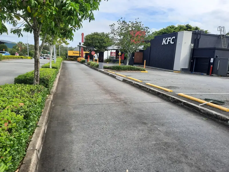 Trimmed hedges lining a KFC drive-through lane